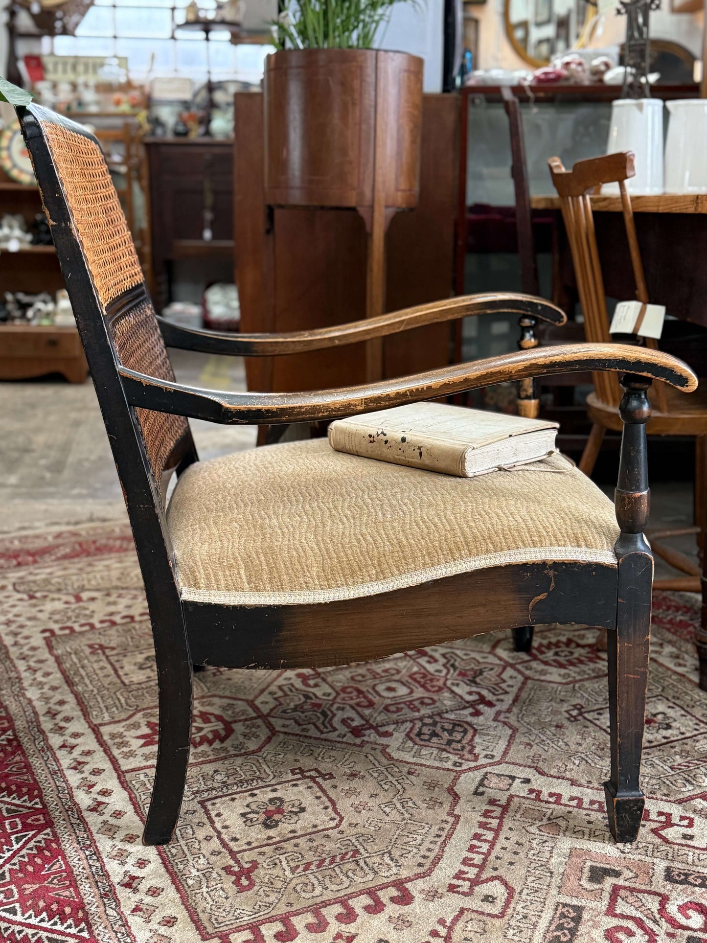 Antique Bergere chair with patina, re-upholstered seat, and book on it, showcasing vintage elegance and sturdy design.